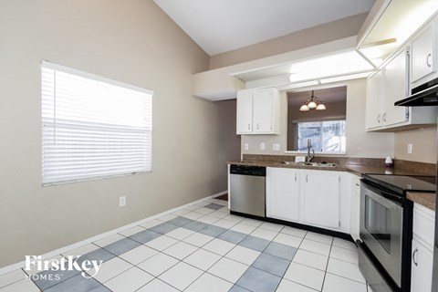 a kitchen with white cabinets and black and white appliances and a window