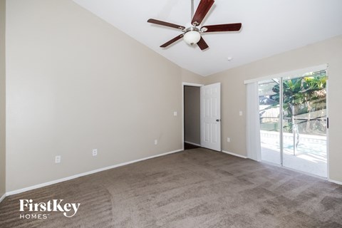 an empty living room with a ceiling fan and a door to a patio