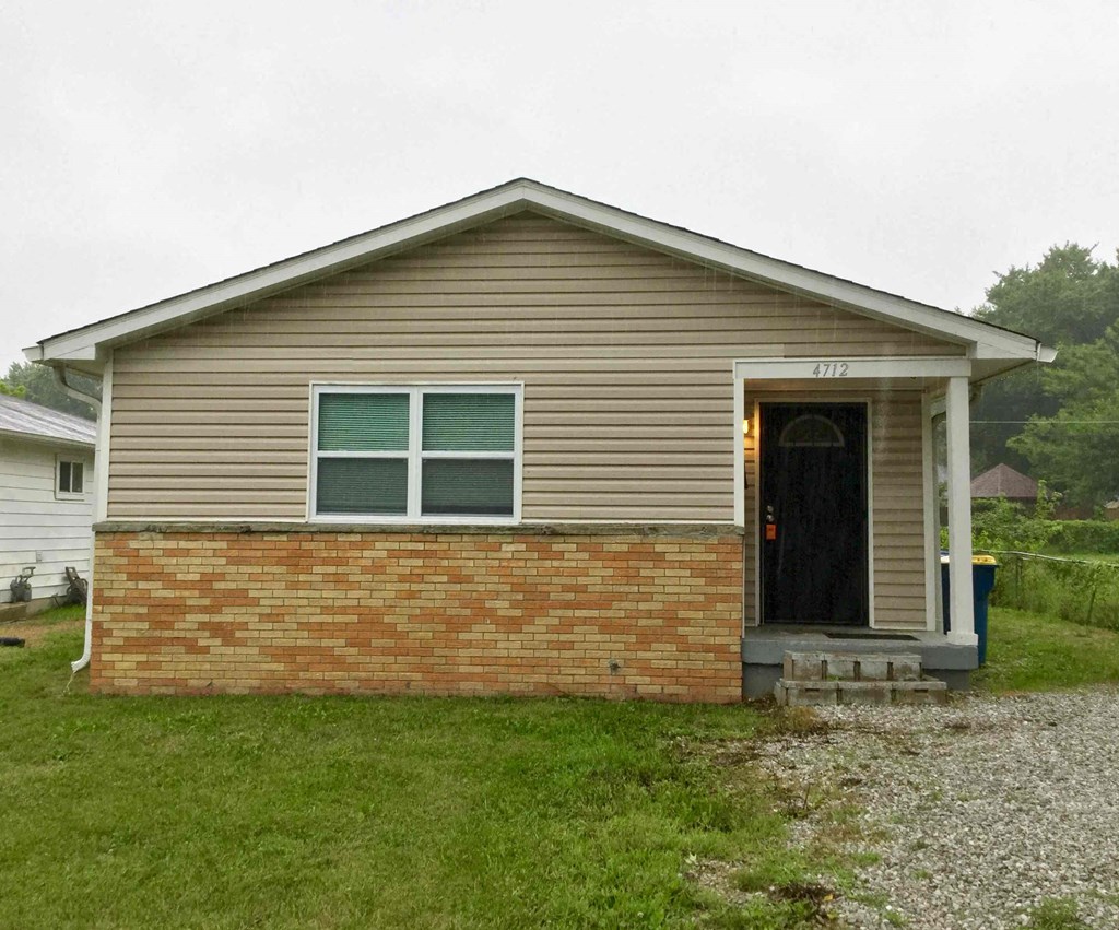 A small house with a brown brick wall and a black door.