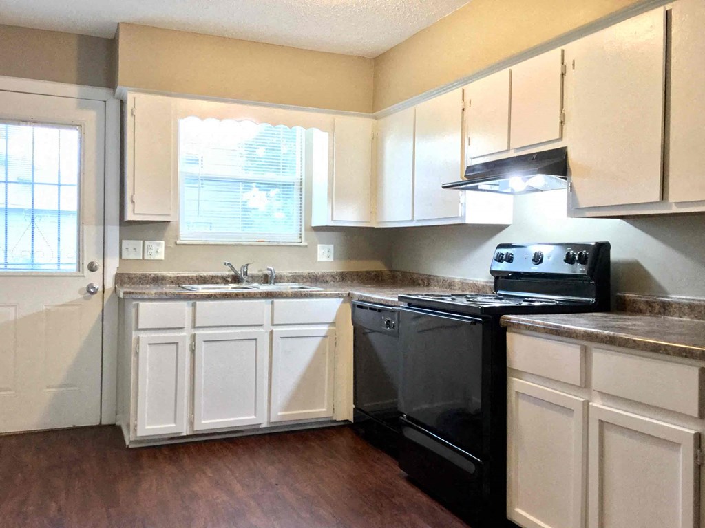 A kitchen with a black stove top oven and white cabinets.