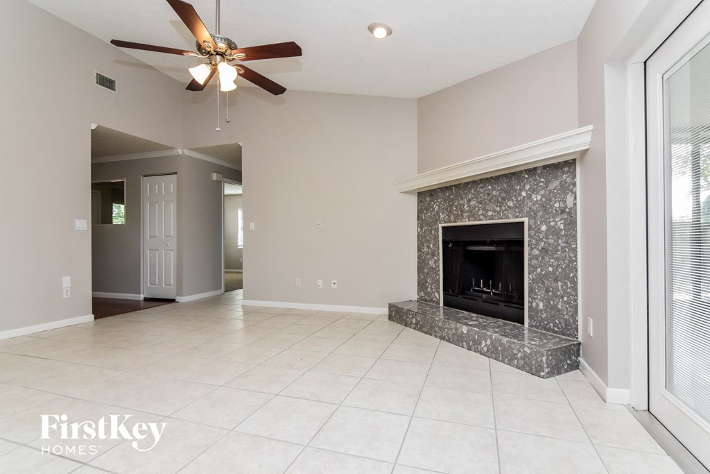 A spacious living room with a fireplace and a ceiling fan.