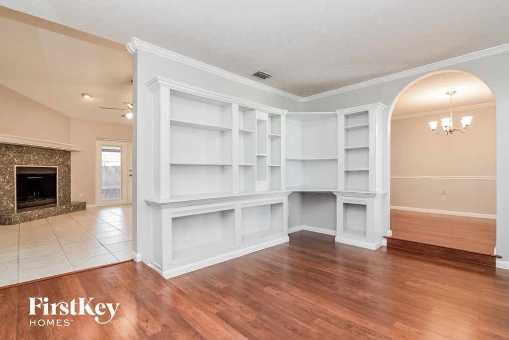 A large, empty room with wooden floors and a fireplace.