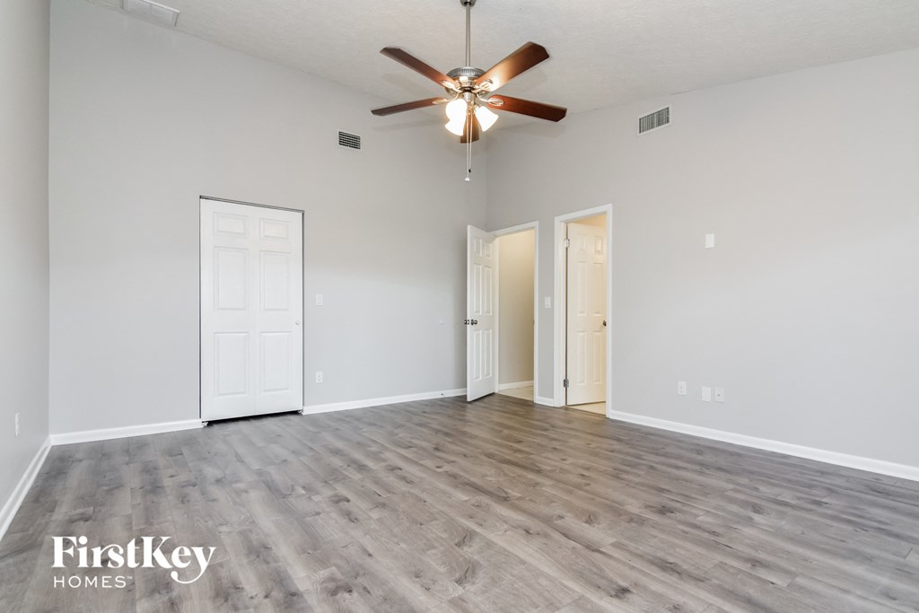 A spacious room with a ceiling fan and wooden flooring.