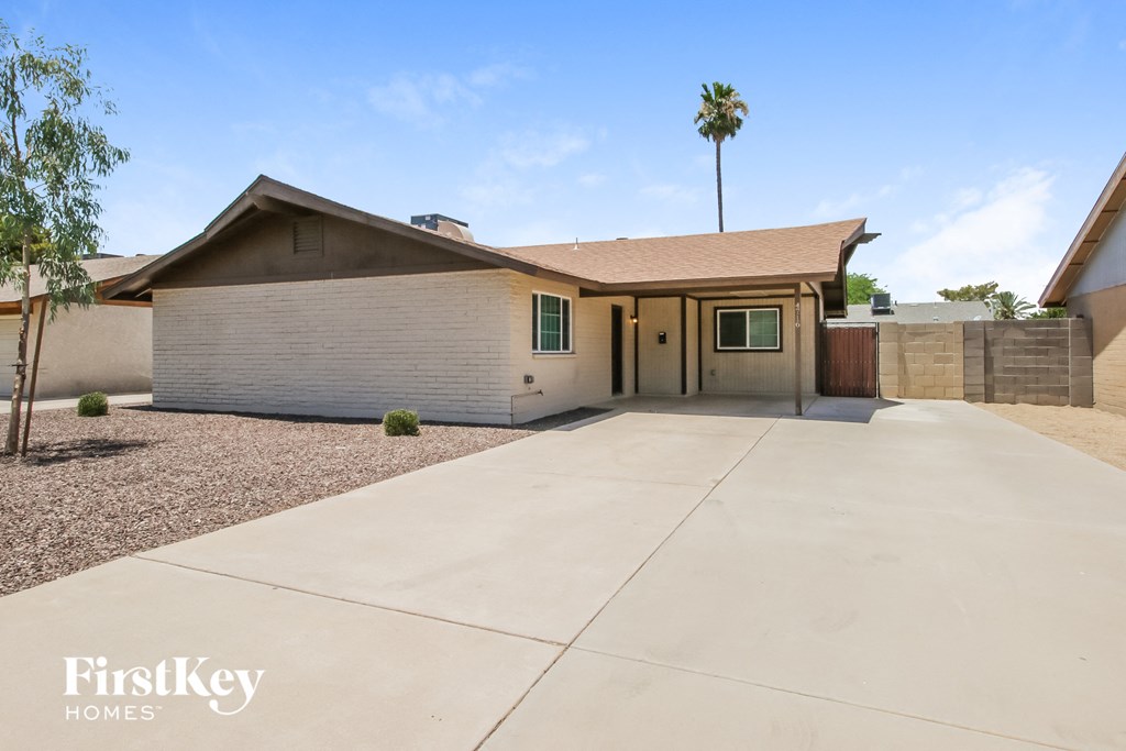 a white house with a driveway and a palm tree