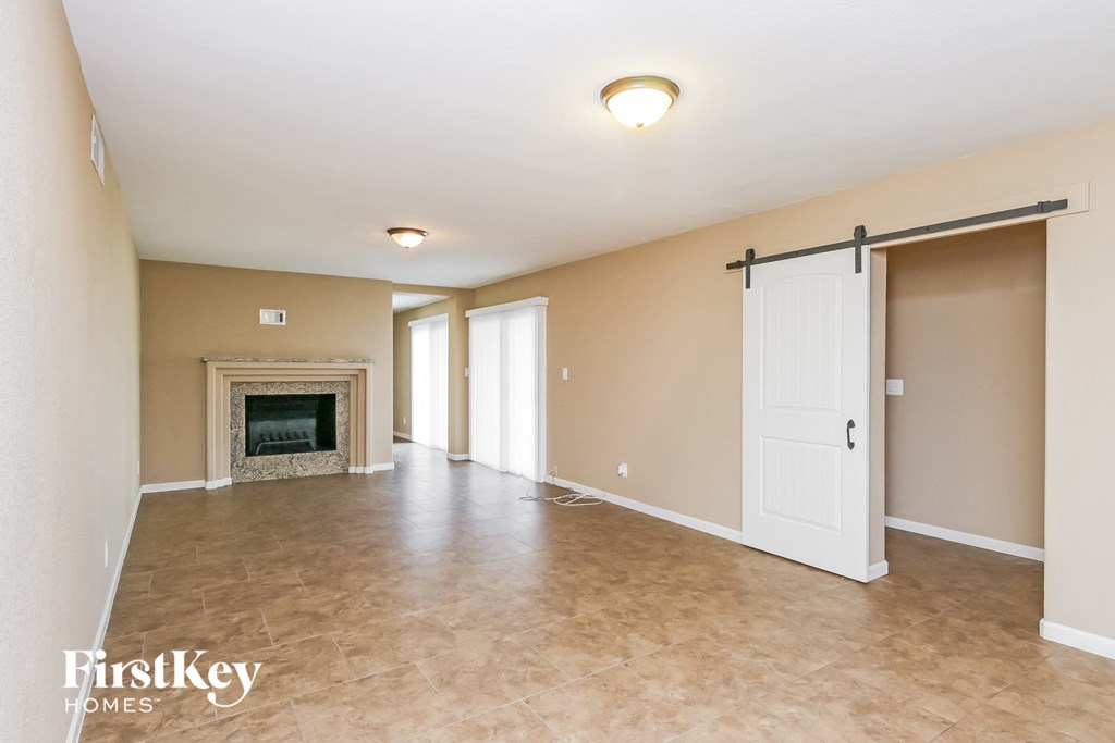 an empty living room with a fireplace and sliding doors