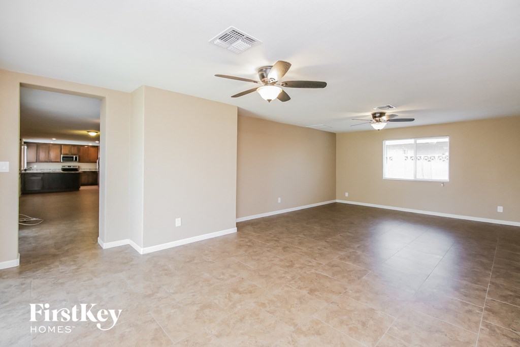 an empty living room with a ceiling fan and tile floors