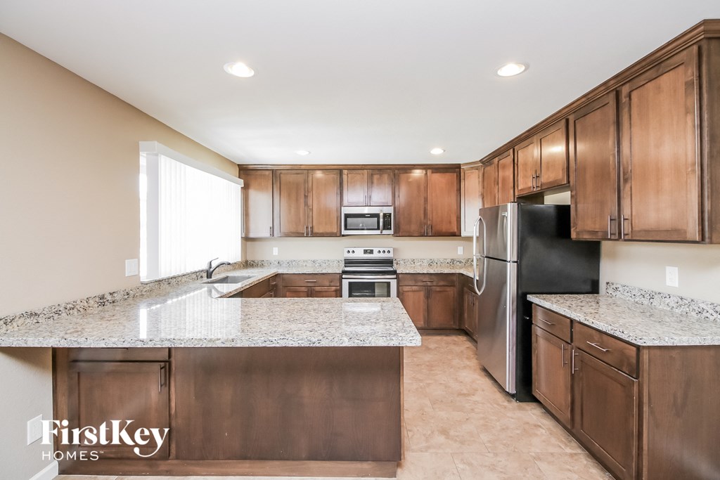 a kitchen with wooden cabinets and granite counter tops and a stainless steel refrigerator