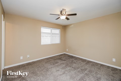the spacious living room with carpet and a ceiling fan