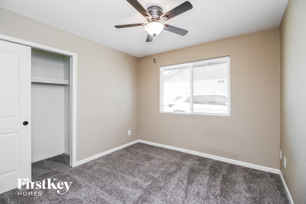 the living room of a home with a ceiling fan and a closet