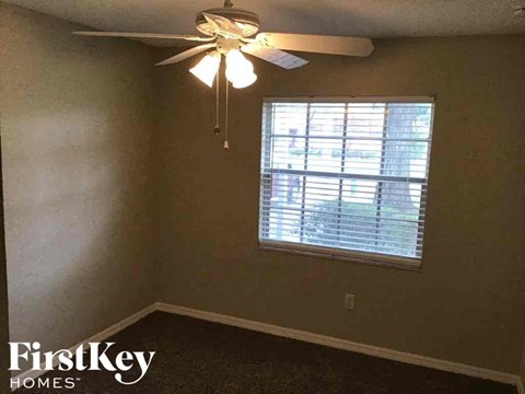 A room with a ceiling fan and a window with blinds.