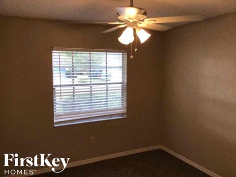A room with a ceiling fan and a window with blinds.