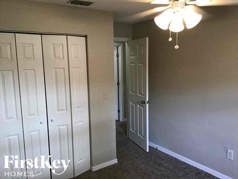 A room with a white door and a ceiling fan.