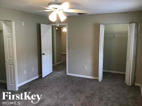 A room with a carpeted floor and a ceiling fan.