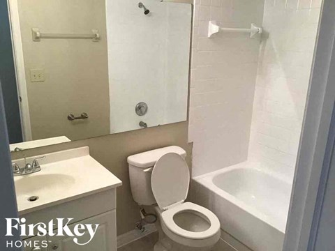 A white toilet in a bathroom with a white sink and a white bathtub.