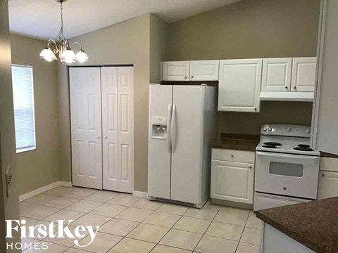 A kitchen with a white refrigerator and cabinets.