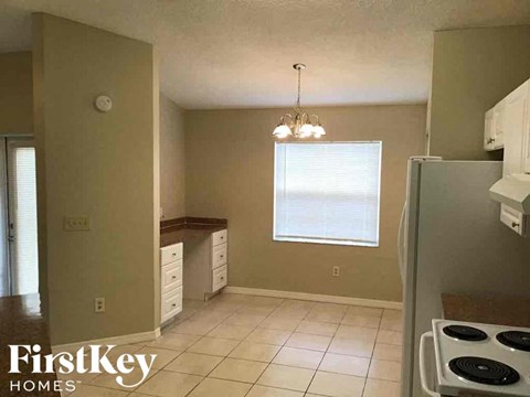 A kitchen with a stove top oven and a window with blinds.