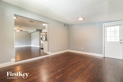 the living room and dining room with wood flooring and a white door