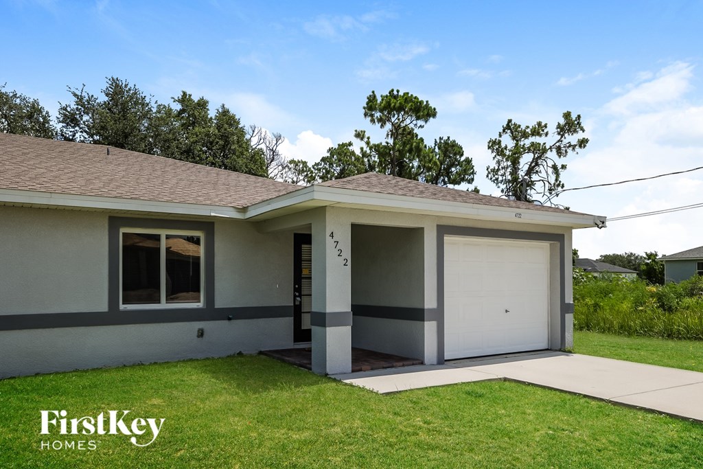 A house with a garage and a tree in front of it.