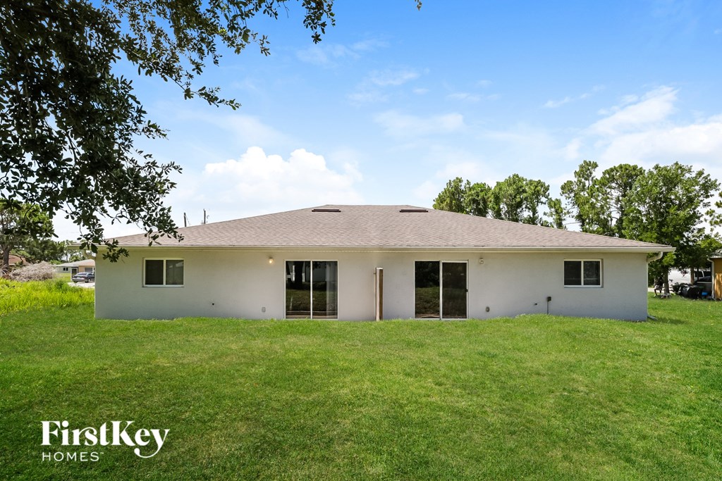 A white house with a brown roof is surrounded by green grass.