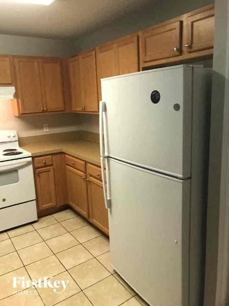 A white refrigerator in a kitchen with wooden cabinets.