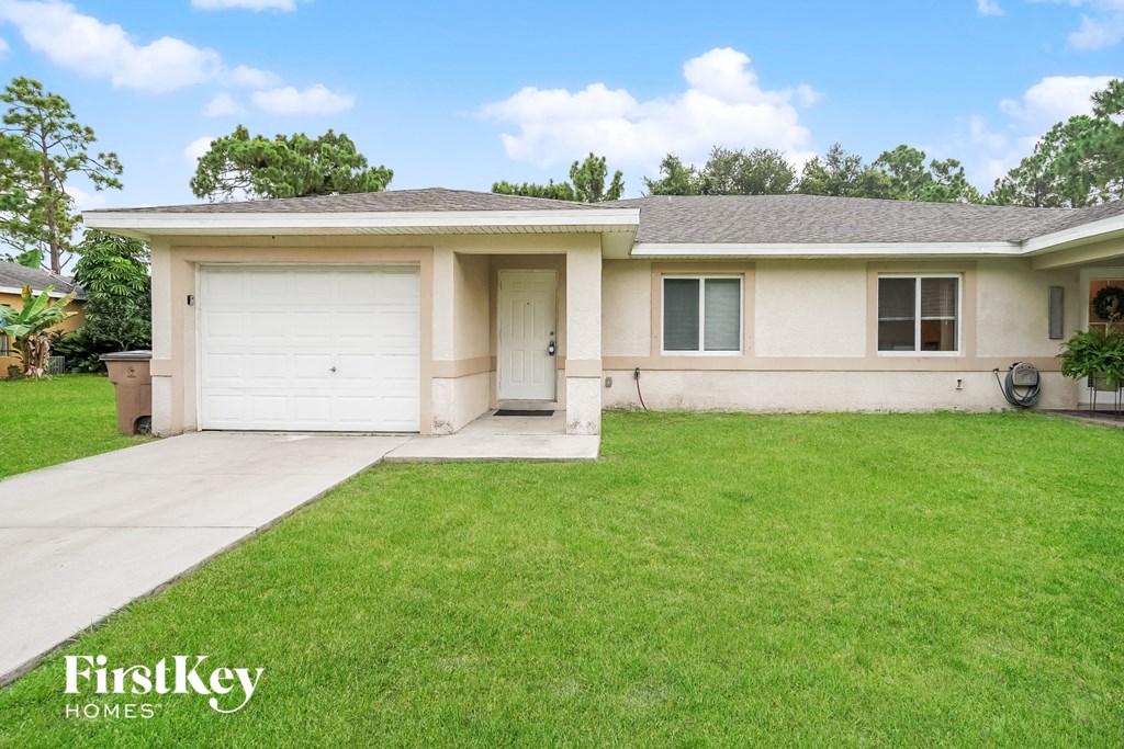 A house with a garage and a driveway in front of it.