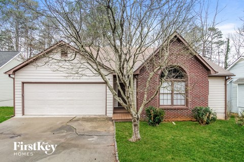a brick home with a white garage door and a tree in the yard