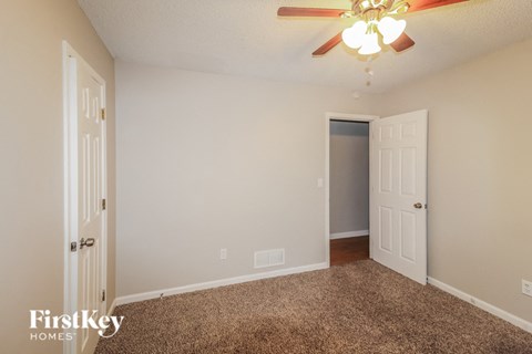 a bedroom with a ceiling fan and a door to a closet
