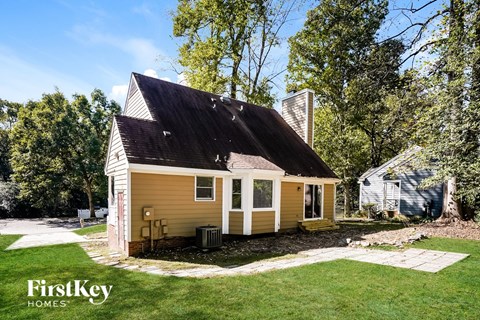 A small house with a porch is surrounded by a grassy yard.
