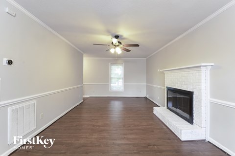 A spacious room with a fireplace and a ceiling fan.