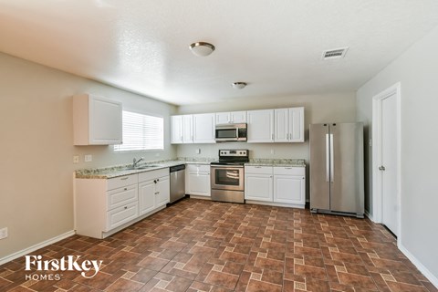 A kitchen with a tile floor and white cabinets.