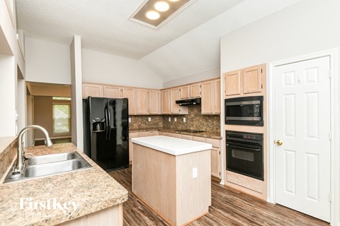 A kitchen with wooden cabinets and a black refrigerator.