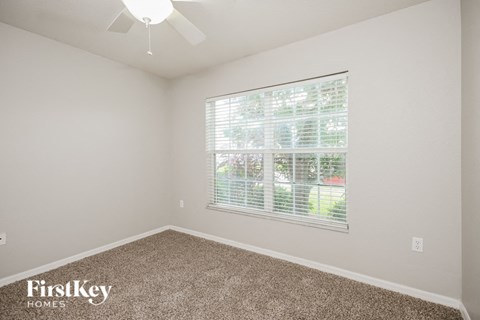 a bedroom with a large window and a carpeted floor