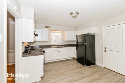 A kitchen with black appliances and white cabinets.