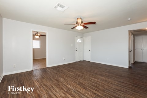 A spacious room with wooden floors and a ceiling fan.