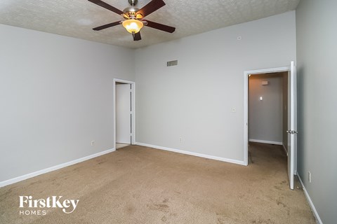 a bedroom with white walls and a ceiling fan