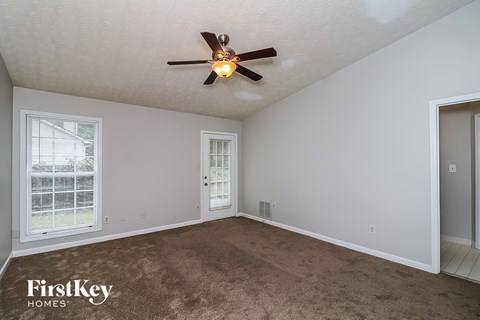 a living room with a ceiling fan and a carpet