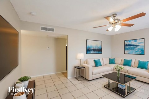 A living room with a white couch and a ceiling fan.