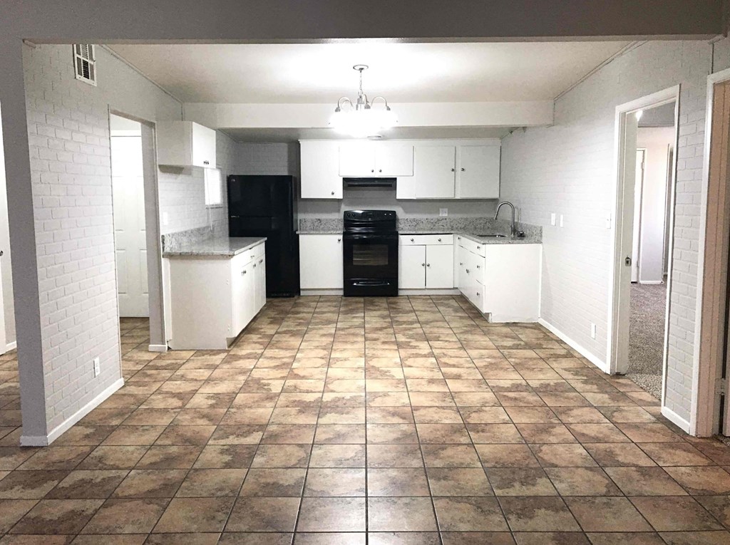 A kitchen with black appliances and white cabinets.