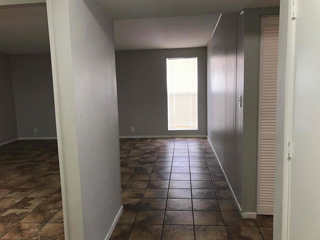 A room with brown tiles on the floor and a window letting in light.