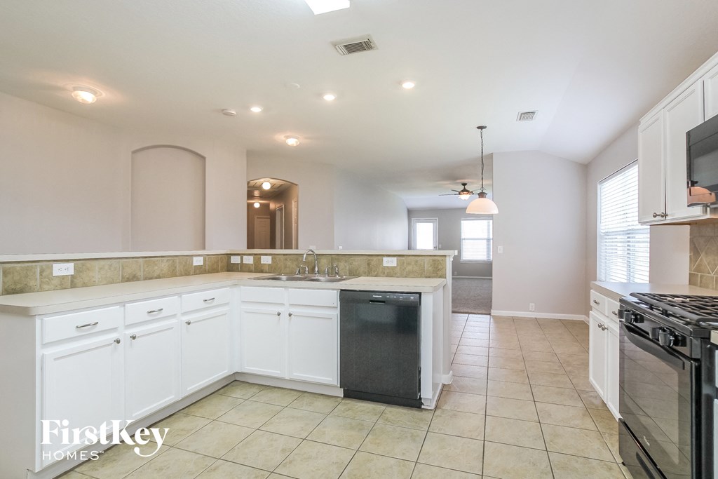 a kitchen with white cabinets and a black dishwasher