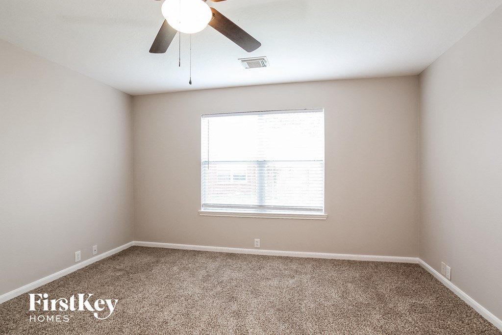 a room with carpet and a window and a ceiling fan