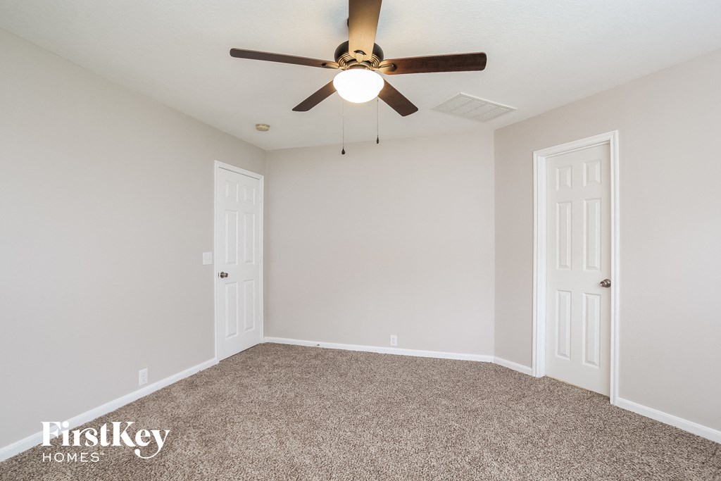 the living room of an empty home with a ceiling fan