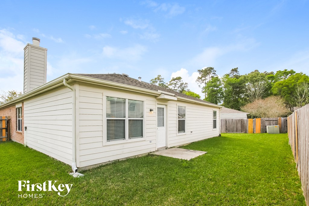the backyard of a white house with a lawn and a fence