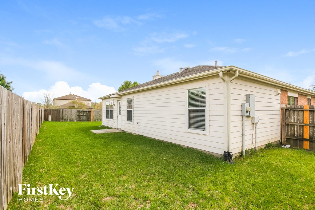 the backyard of a white house with a yard and a fence