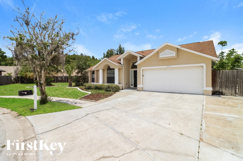 a beige house with a driveway and a garage door