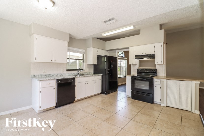 a kitchen with white cabinets and black appliances