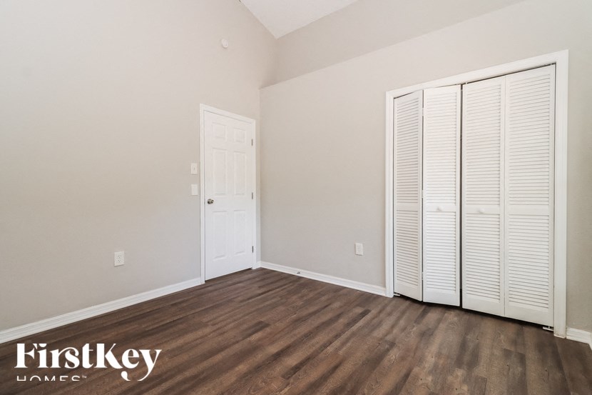 a bedroom with wooden floors and white closet doors