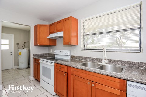 A kitchen with orange cabinets and a white dishwasher.