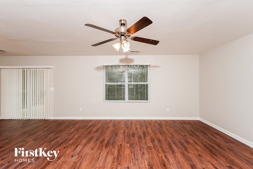 A room with a ceiling fan and wooden flooring.