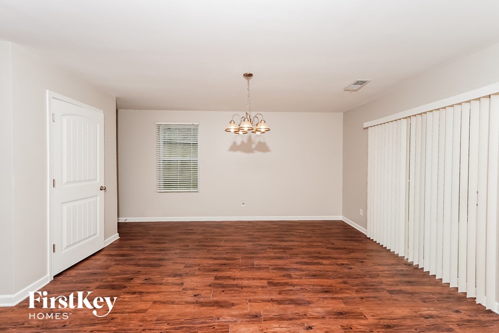A room with wooden floors and a chandelier hanging from the ceiling.